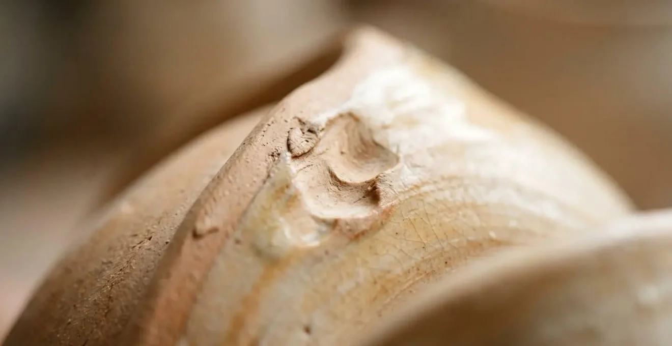 Extreme close-up macro shot of hand-thrown Japanese pottery surface showing authentic irregular textures and natural glaze variations