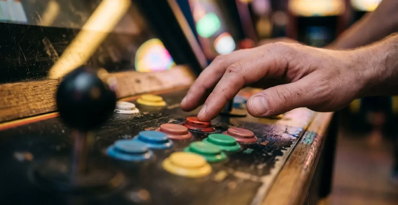 Close-up view of hands positioned on a rhythm game cabinet control panel demonstrating proper arcade etiquette