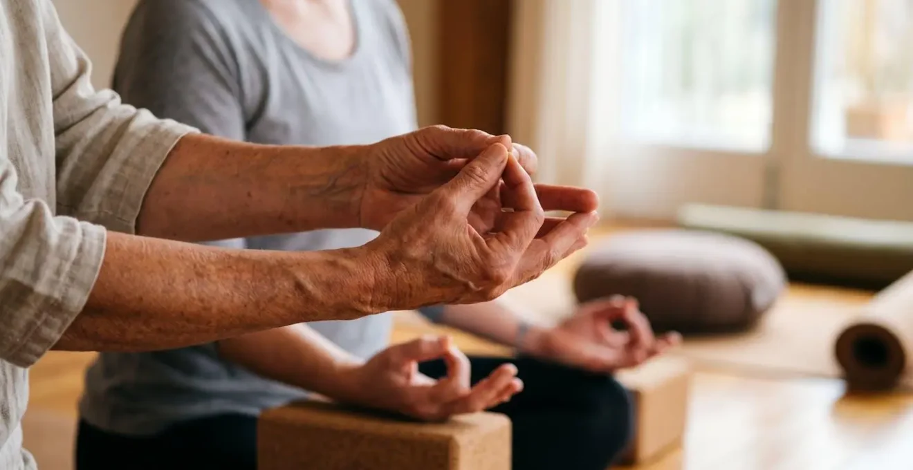 Close-up of experienced yoga teacher's hands demonstrating precise alignment adjustment with natural window light